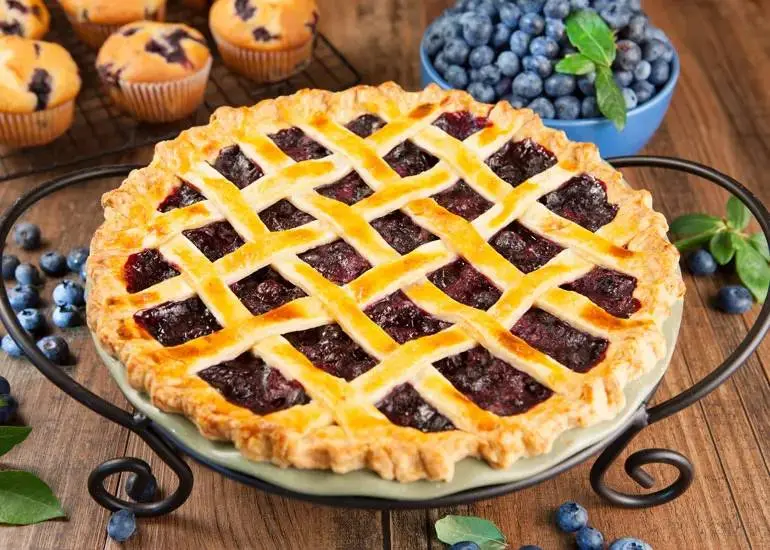 A blueberry pie with a lattice crust is presented on a table.