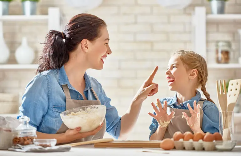 Mother and daughter being playful while making bread dough.