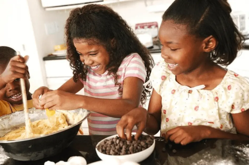 Baking with Kids - Three children smiling while baking cookies in a home kitchen
