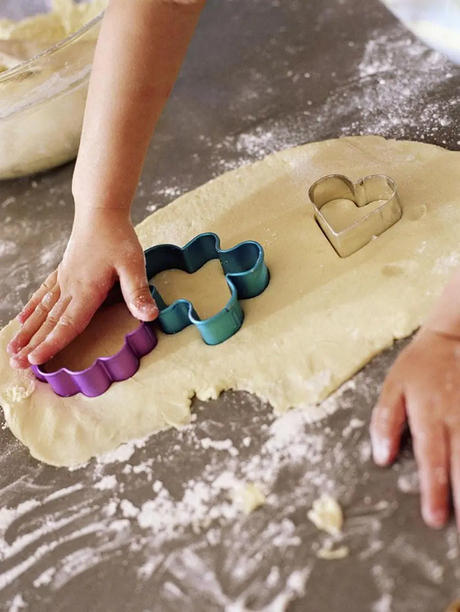 Baking with Kids - A child's hands shaping cookies with cookie cutters. A fun and delicious activity for little ones