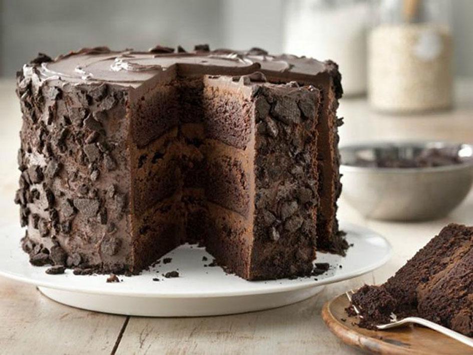 Three layer chocolate cake with slice cut out and displayed