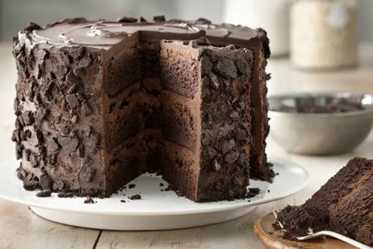 Three layer chocolate cake with slice cut out and displayed