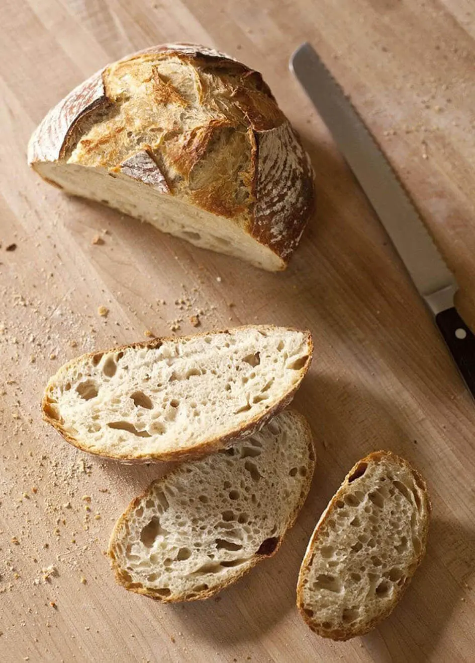 Sliced Yeast bread loaf made from Gold Medal Flour on a cutting board with knife ready for serving.